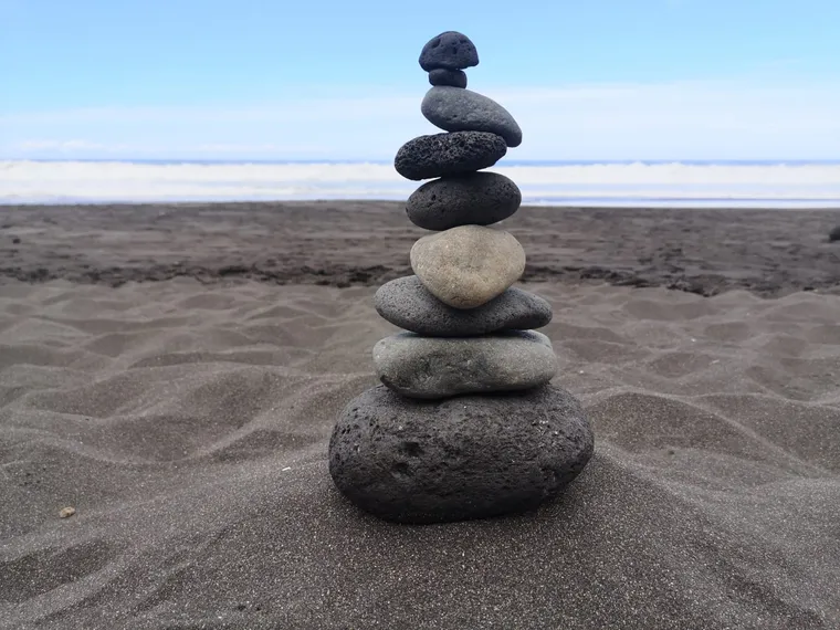 Sorgsam aufeinandergeschichtete Steine am Strand – Sinnbild für Balance und wiedergefundenen Halt
