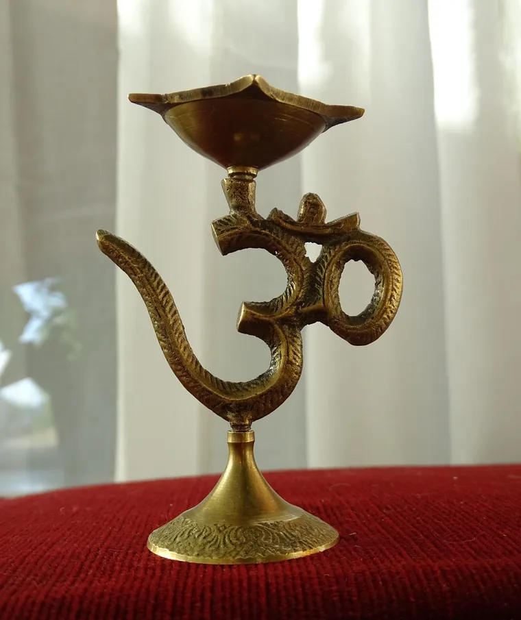 Messing-Öllampe mit Om-Zeichen auf rotem Tuch